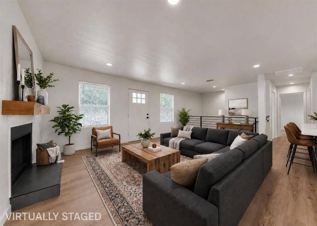 1719 Boot Hill Road, Granbury, TX 76049 Open-concept living space featuring wood-finish flooring, recessed lighting, a fireplace with a wood mantel, and a horizontal metal railing