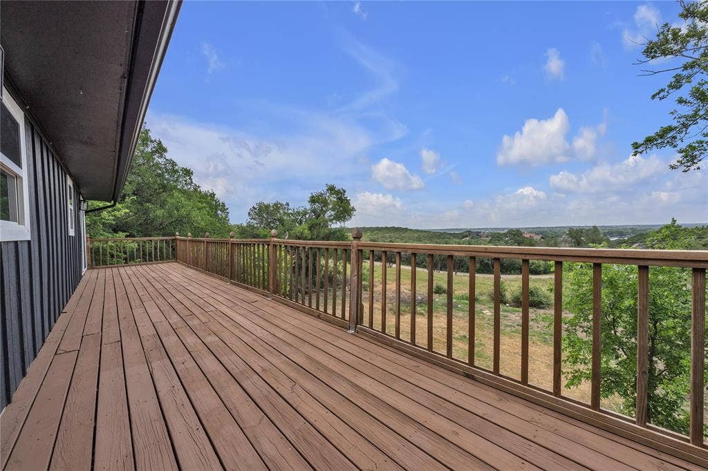 1719 Boot Hill Road, Granbury, TX 76049 Expansive wood deck featuring vertical wood balusters and a post-and-rail railing system, complemented by extensive natural landscape scenery