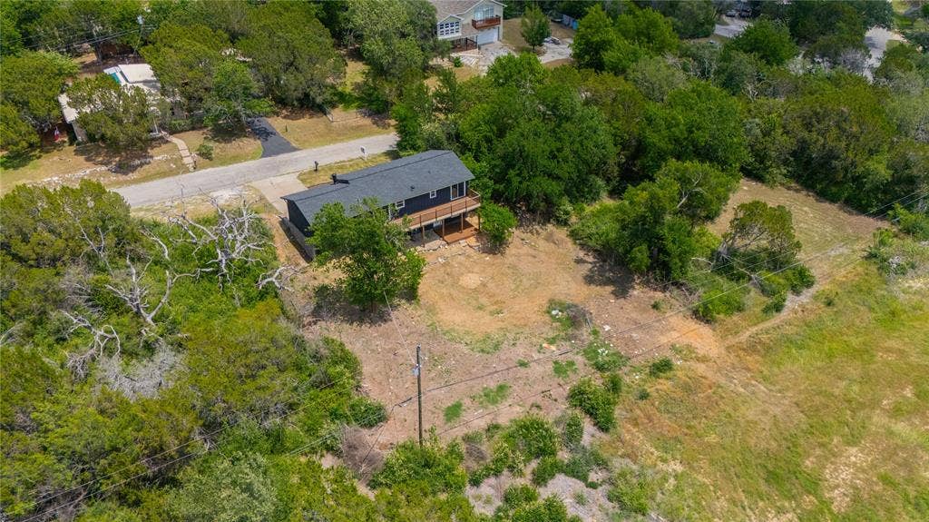 1719 Boot Hill Road, Granbury, TX 76049 Two-story residential structure featuring a dark-toned exterior, dark shingle roof, and an elevated wood deck