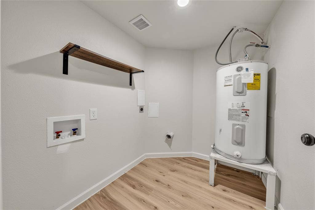 1719 Boot Hill Road, Granbury, TX 76049 Utility space featuring wood-finish flooring, a mounted wall shelf with black metal brackets, and a recessed water supply box