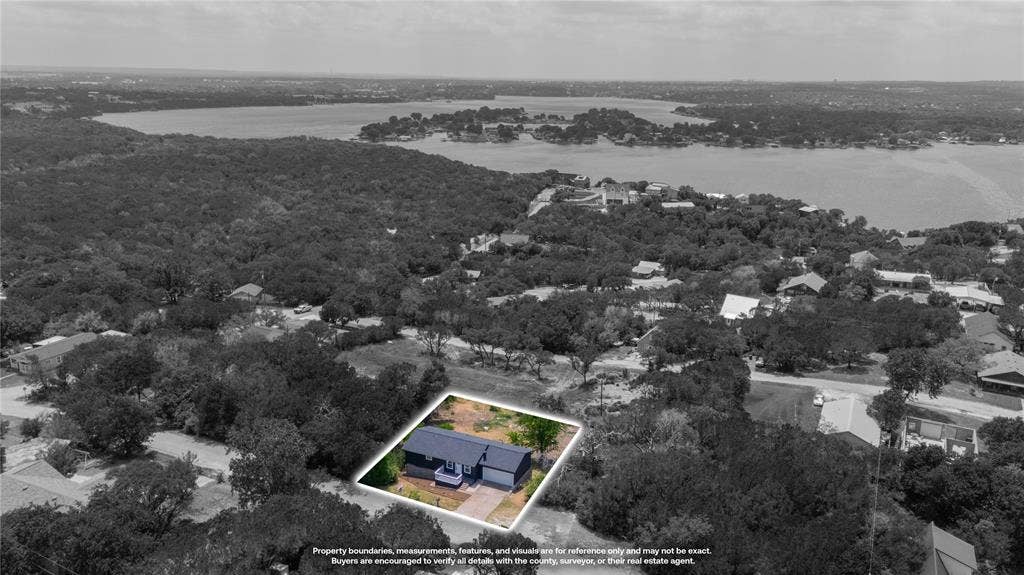 1719 Boot Hill Road, Granbury, TX 76049 Single-story residential structure featuring a dark-toned exterior, a front-facing attached garage, and a paved driveway, situated within a wooded lot