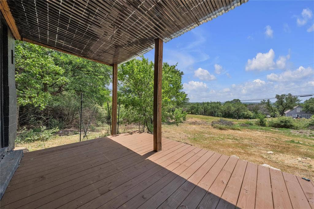 1719 Boot Hill Road, Granbury, TX 76049 Covered deck featuring wood-finish decking, timber support posts, and a corrugated overhead canopy