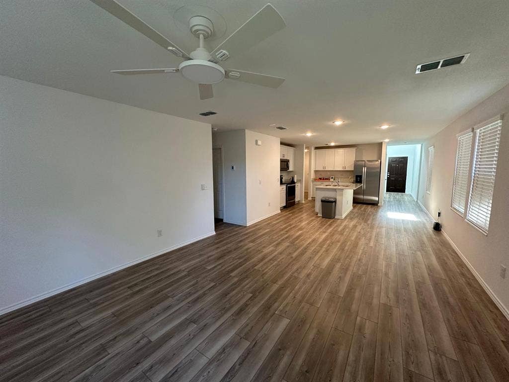 821 POPPY COVE Lane, Princeton, TX 75407 Open-concept interior featuring wood-finish flooring, a kitchen island, white cabinetry, stainless steel appliances, and a ceiling fan