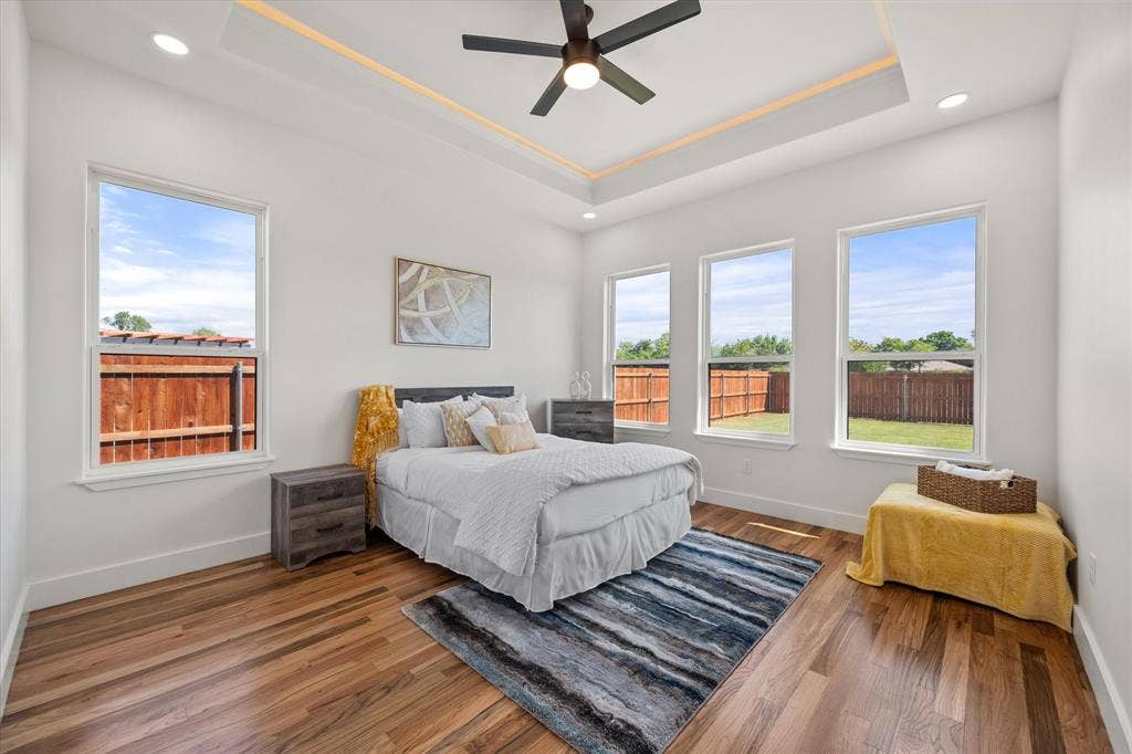 122 Yvonne Street, Red Oak, TX 75154 Room featuring a tray ceiling with recessed lighting, wood-finish flooring, a matte black ceiling fan, and large windows
