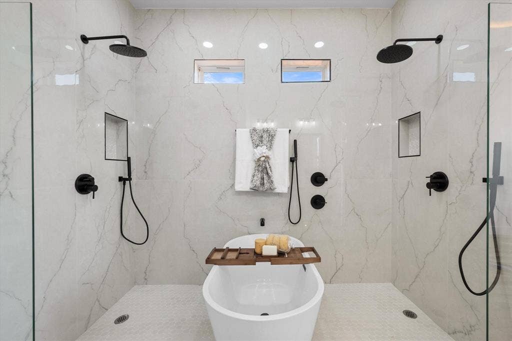 122 Yvonne Street, Red Oak, TX 75154 Walk-in wet room featuring a freestanding soaking tub, dual rainfall showerheads, matte black fixtures, built-in wall niches, and floor-to-ceiling stone-look tiling