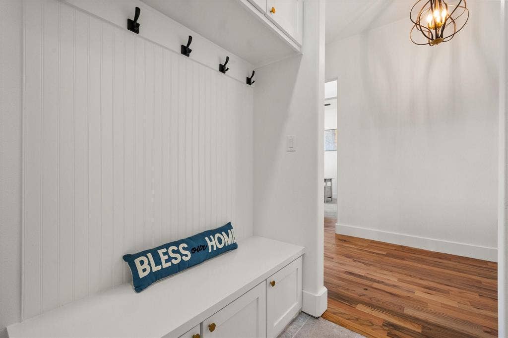 122 Yvonne Street, Red Oak, TX 75154 Built-in mudroom bench with beadboard paneling, matte black wall-mounted coat hooks, overhead cabinetry, and Oak wood flooring