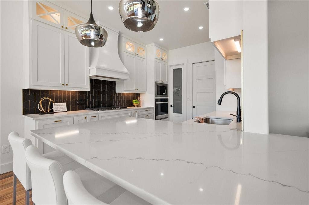 122 Yvonne Street, Red Oak, TX 75154 Quartz countertops with a black-gold tiled backsplash, 42" cabinets with upper cabinets with glass inserts and lighting