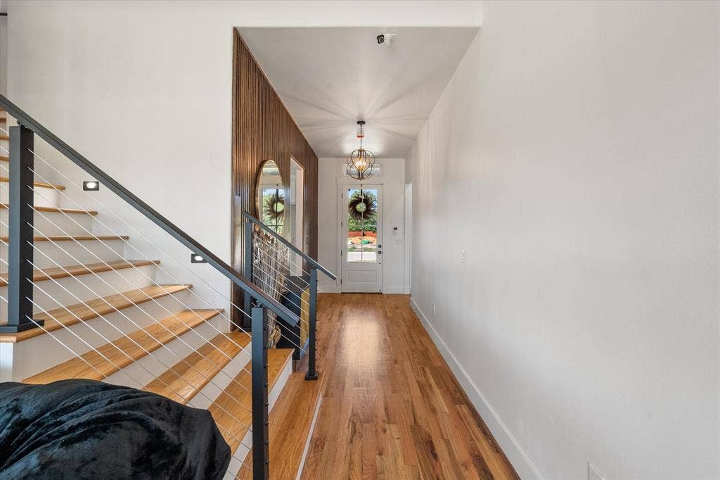 122 Yvonne Street, Red Oak, TX 75154 Foyer featuring wood-finish flooring, a wood-slat accent wall, a staircase with cable railing, and a decorative orb-style pendant light fixture