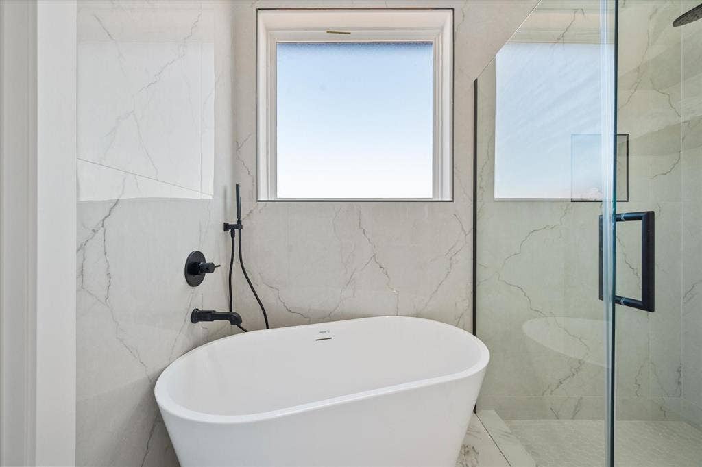 122 Yvonne Street, Red Oak, TX 75154 Freestanding soaking tub featuring matte black plumbing fixtures, oversized large-format tile surround, glass-enclosed shower, and built-in wall niche