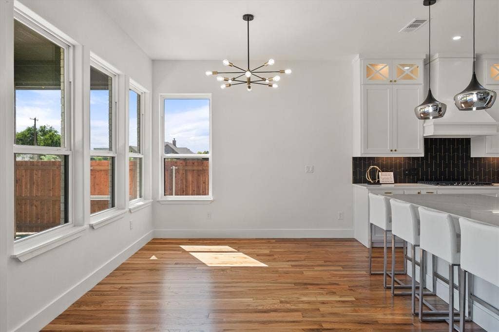 122 Yvonne Street, Red Oak, TX 75154 Open-concept space featuring wood-finish flooring, a modern multi-arm chandelier, white shaker-sty