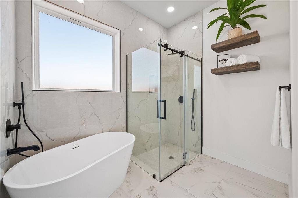 122 Yvonne Street, Red Oak, TX 75154 Freestanding soaking tub with matte black fixtures, glass-enclosed shower with matte black hardware, lwall-mounted wood shelving