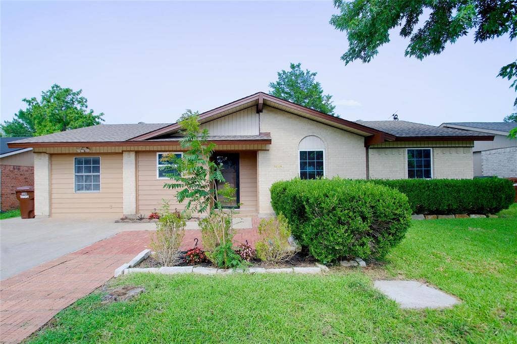 2708 N Avenue, Plano, TX 75074 Single-story residence featuring a mixed brick and horizontal siding exterior, a low-pitch roofline, an attached garage, and a brick-paved walkway
