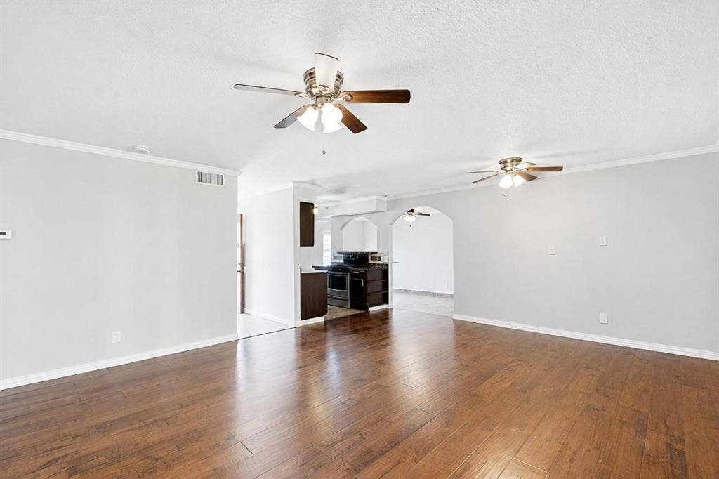 2708 N Avenue, Plano, TX 75074 Wood-finish flooring, dual ceiling fans with integrated lighting, neutral wall paint, and architectural arched doorways