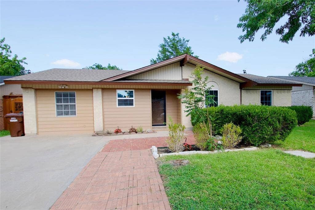 2708 N Avenue, Plano, TX 75074 Single-story exterior featuring a brick and horizontal siding facade, low-pitch roofline, concrete driveway, and red brick paver walkway
