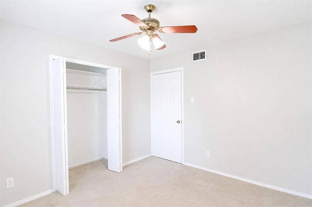 2708 N Avenue, Plano, TX 75074 Neutral-toned interior featuring wall-to-wall carpeting, a six-panel interior door, a bi-fold closet door, and a ceiling fan with integrated light fixture