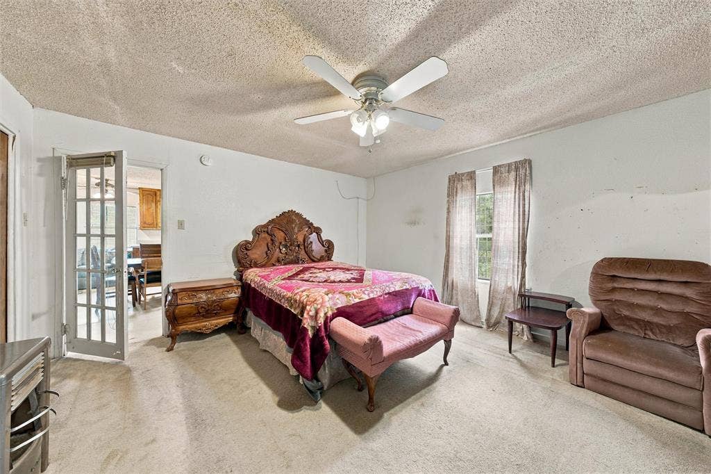 1703 Arra Street, Waco, TX 76704 Interior space featuring a textured ceiling, neutral-tone carpeting, a white multi-panel door with glass inserts, and a central ceiling fan with integrated lighting