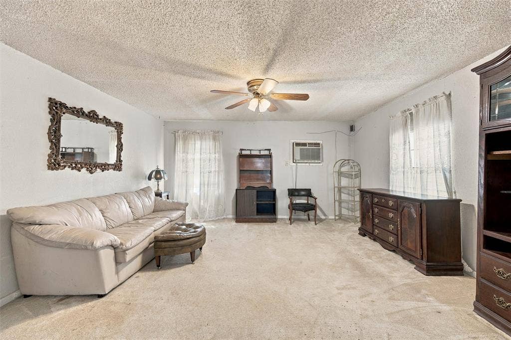 1703 Arra Street, Waco, TX 76704 Living area featuring a textured ceiling, neutral wall tones, carpeted flooring, and a central ceiling fan with integrated lighting