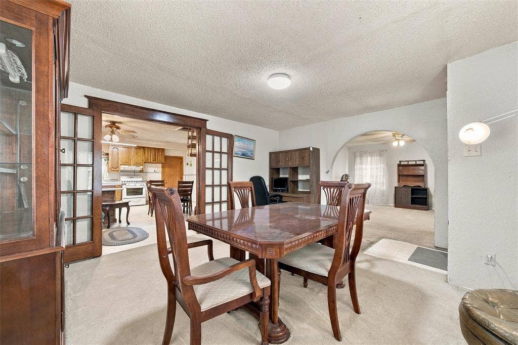 1703 Arra Street, Waco, TX 76704 Room featuring dual glass-panel wood-frame doors, a prominent arched wall opening, and wall-mounted light fixture