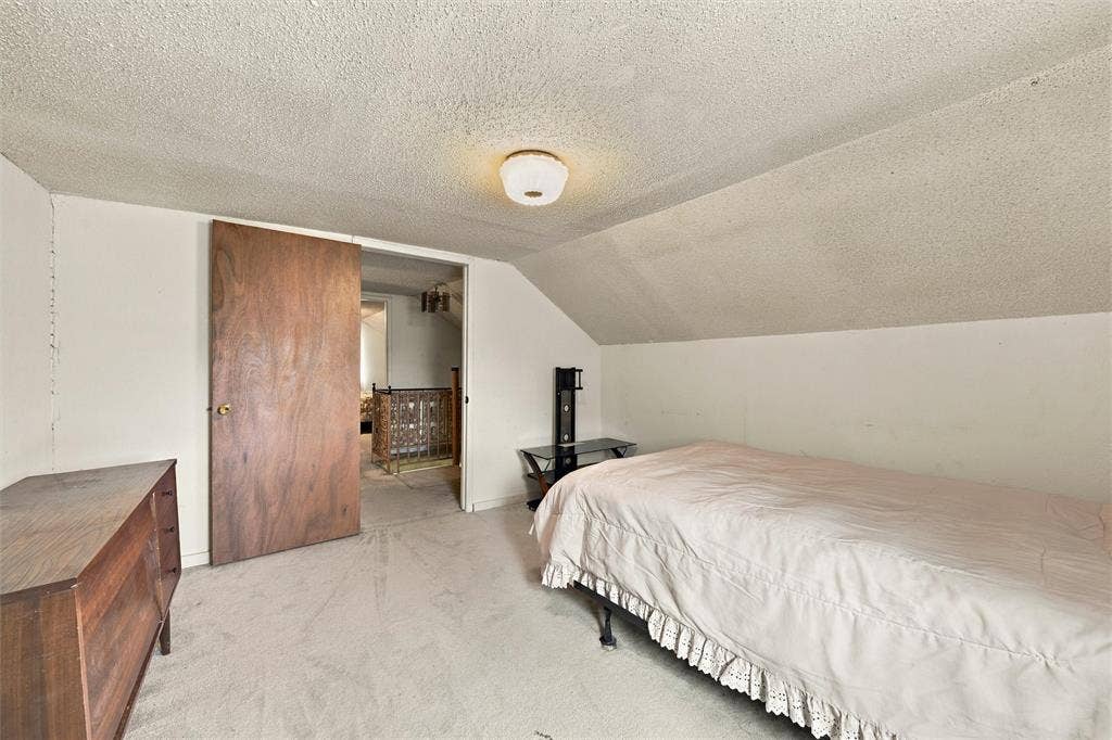 1703 Arra Street, Waco, TX 76704 Interior room featuring a sloped ceiling, wall-to-wall carpeting, a solid wood door, and a flush-mount ceiling light fixture