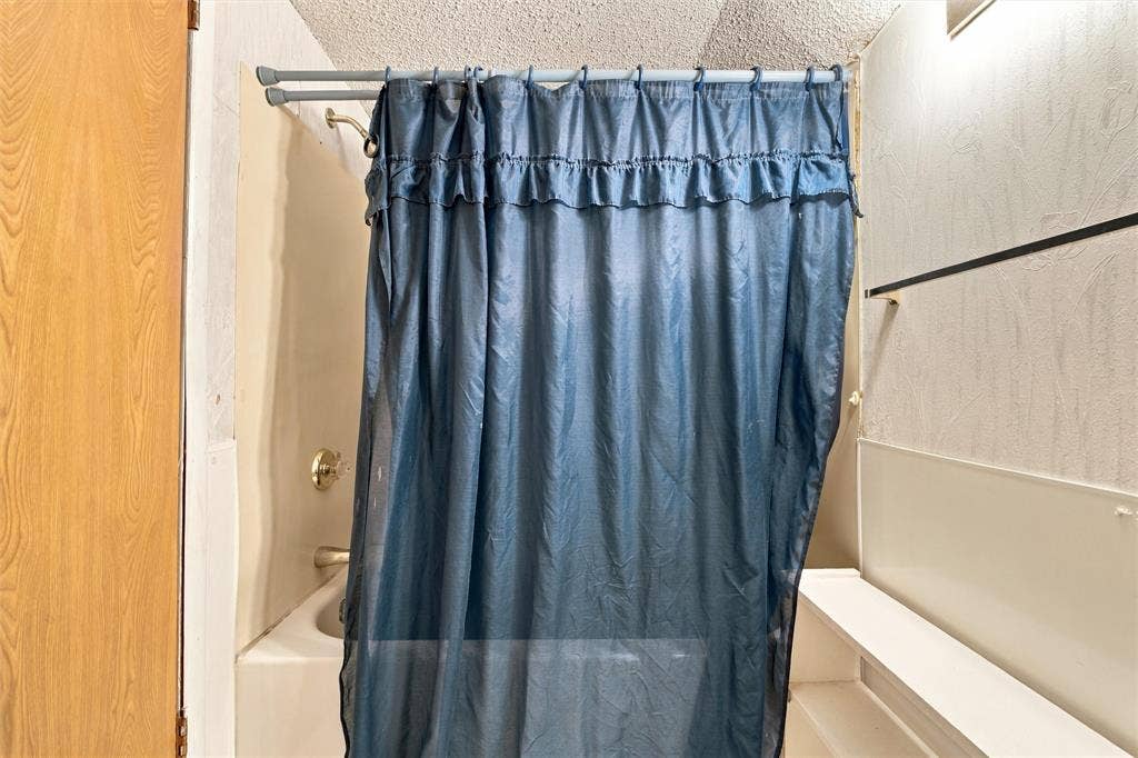 1703 Arra Street, Waco, TX 76704 Bathtub enclosure featuring integrated wall panels, a metal showerhead, and a wall-mounted faucet fixture