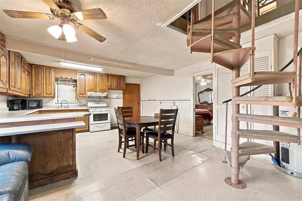 1703 Arra Street, Waco, TX 76704 Kitchen featuring custom wood cabinetry, a peninsula counter, and a metal spiral staircase with treads