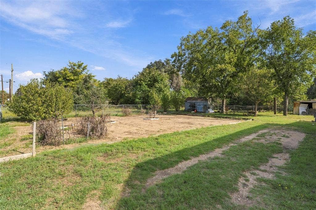 1703 Arra Street, Waco, TX 76704 Expansive backyard featuring mature trees, perimeter chain-link fencing, and a detached storage structure