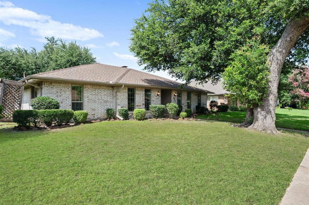 621 Harvest Glen Drive, Richardson, TX 75081 Single-story brick exterior featuring a hipped roof, grid-pattern windows, and established landscaping including a large mature tree and manicured lawn