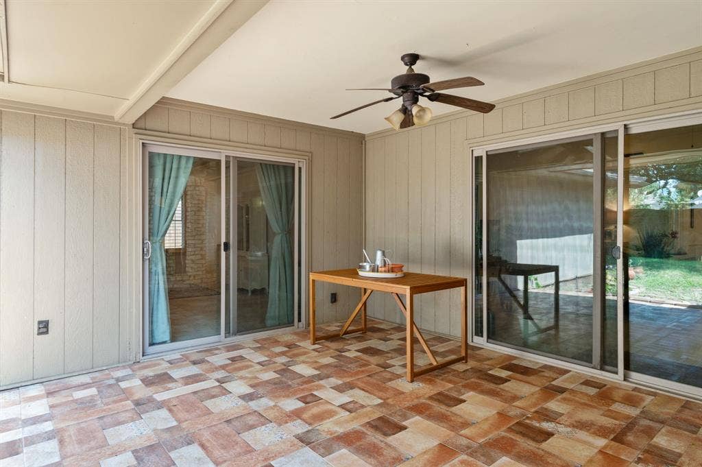 621 Harvest Glen Drive, Richardson, TX 75081 Covered patio featuring multi-toned tile flooring, vertical siding, two sets of glass sliding doors, and a ceiling-mounted fan
