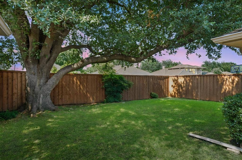 621 Harvest Glen Drive, Richardson, TX 75081 Backyard featuring a grass lawn, mature tree, and vertical wood fencing