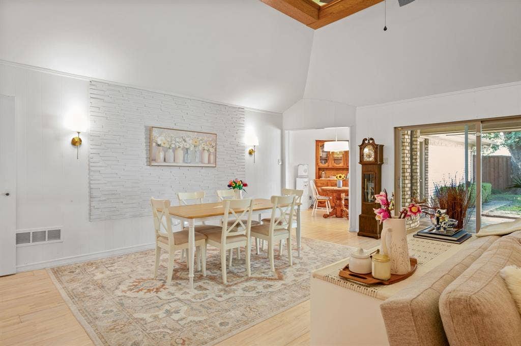621 Harvest Glen Drive, Richardson, TX 75081 Vaulted ceilings, textured stone accent wall, wood-finish flooring, wall-mounted light fixtures, and sliding glass doors