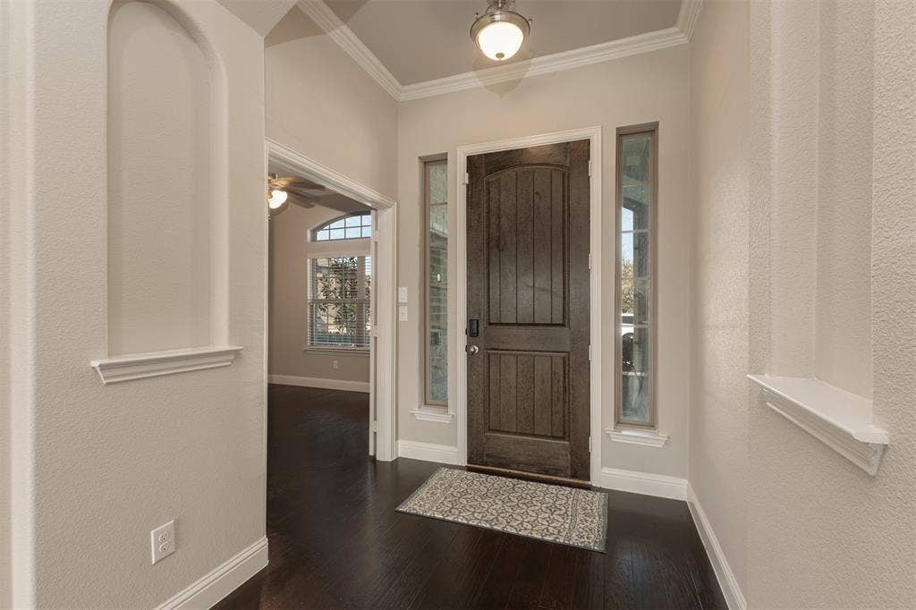 1742 Amalfi Drive, McLendon Chisholm, TX 75032 Foyer featuring wood-finish flooring, recessed wall niches, dark-stained wood entry door, sidelight windows, and crown molding