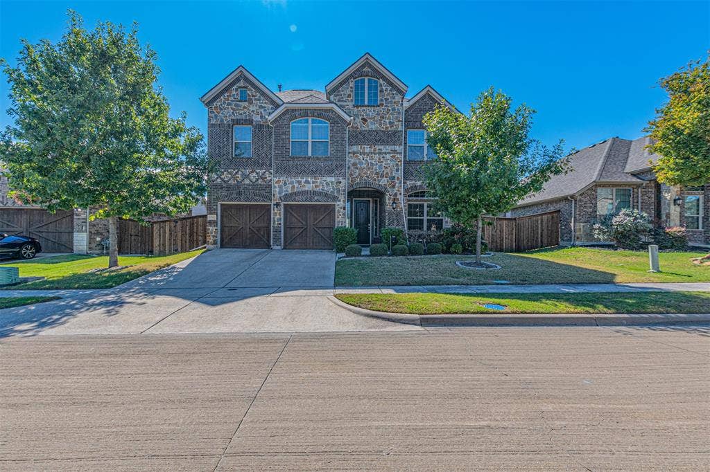 1742 Amalfi Drive, McLendon Chisholm, TX 75032 Two-story exterior featuring multi-textured stone and brick masonry, double-gabled roofline, arched window detailing, and carriage-style garage doors