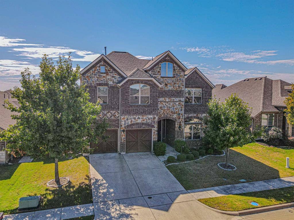 1742 Amalfi Drive, McLendon Chisholm, TX 75032 Multi-story exterior featuring a stone and brick facade, decorative cross-pattern brickwork, arched windows, and carriage-style garage doors