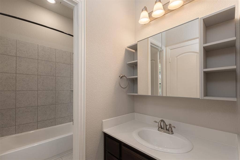 1742 Amalfi Drive, McLendon Chisholm, TX 75032 Bathroom featuring a vanity with a white countertop, inset sink, and integrated mirrored cabinetry with side shelving