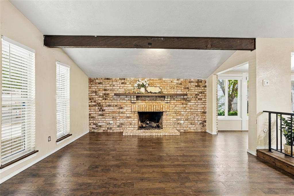 1901 Dodge Trail, Grand Prairie, TX 75052 Inviting living room with vaulted ceilings, exposed wood beams, wood-look flooring, and a striking brick fireplace.