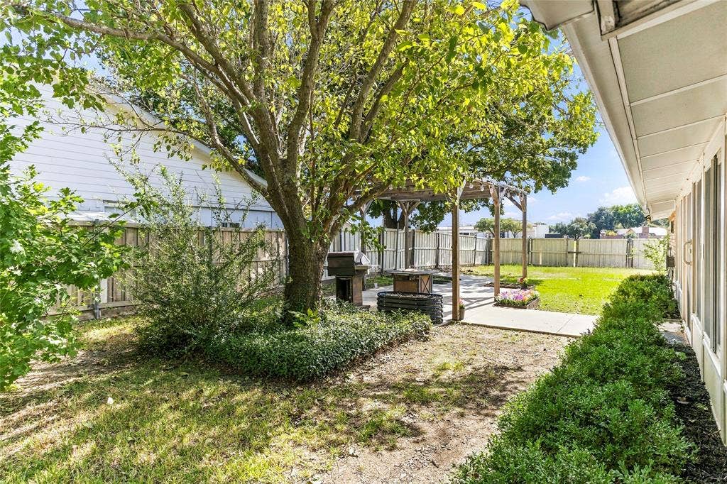 1901 Dodge Trail, Grand Prairie, TX 75052 Rear and side exterior view highlighting the brick exterior, mature shade trees, and expansive backyard with privacy fencing.