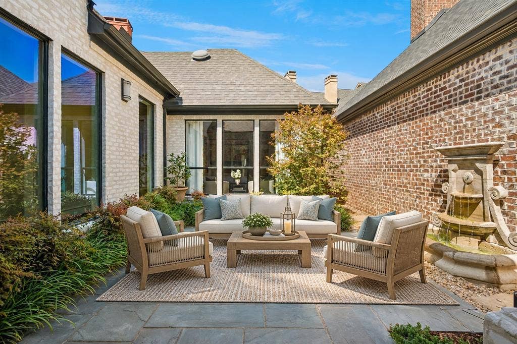 Landscaped courtyard with stone patio and fountain (virtually staged)
