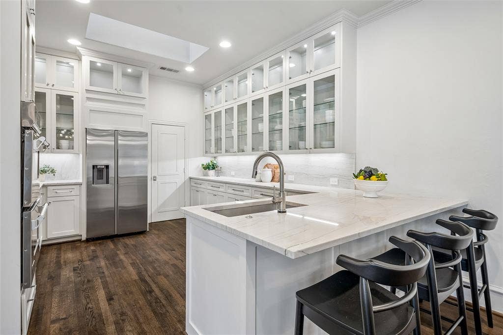 Kitchen features ustom glass-front upper cabinets, quartz counter tops, and a large walk-in pantry with coffee bar
