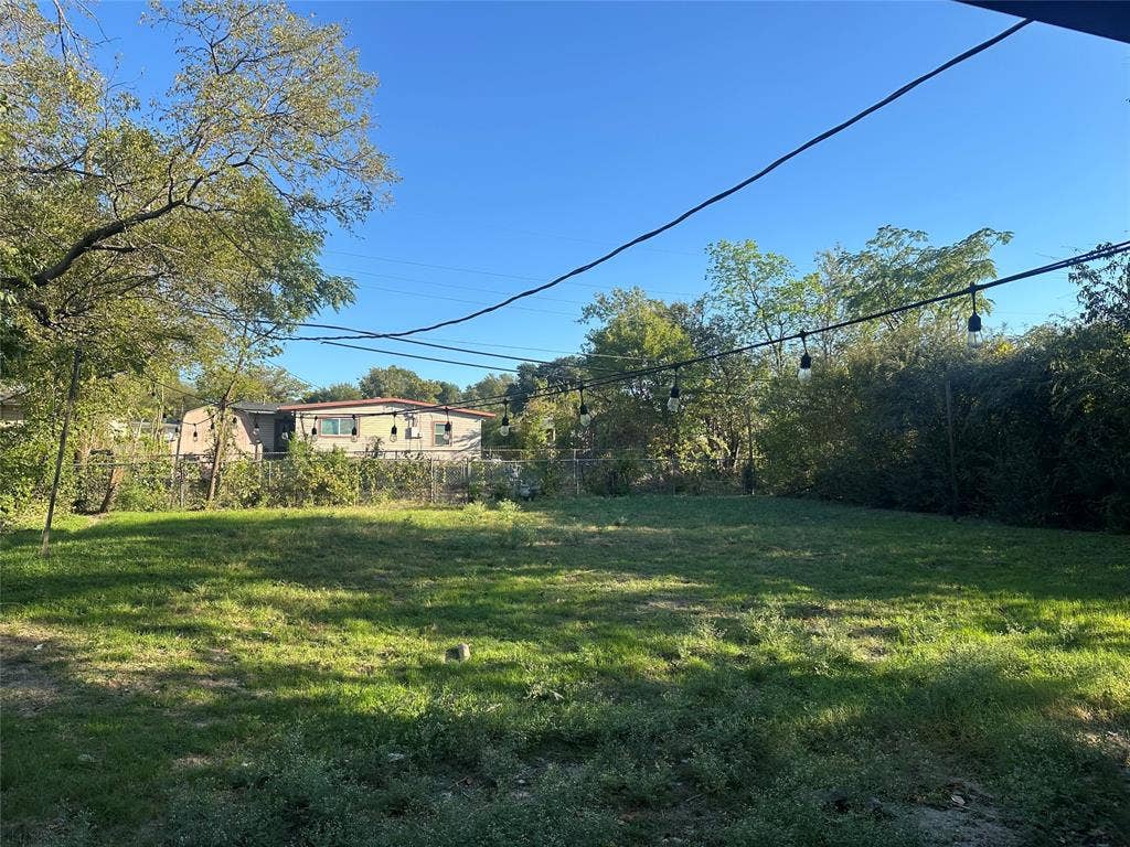 11809 Oberlin Drive, Dallas, TX 75243 Expansive backyard featuring a fenced perimeter, mature trees, and overhead string lighting