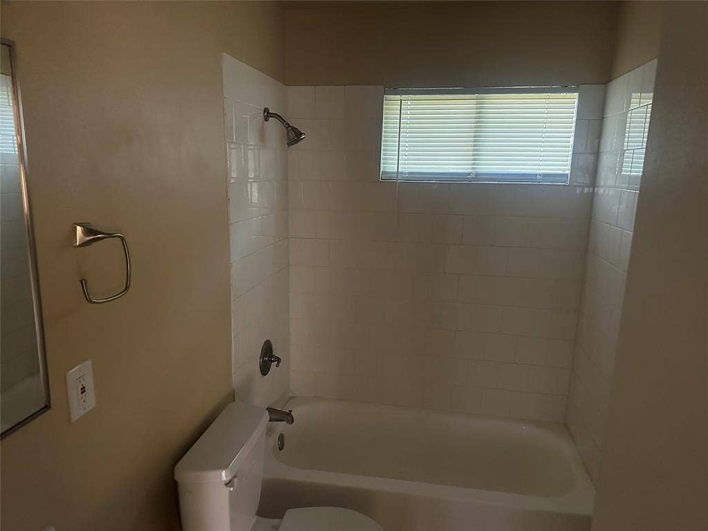 11809 Oberlin Drive, Dallas, TX 75243 Tub and shower combination featuring white subway tile surround, polished metal fixtures, and a recessed window