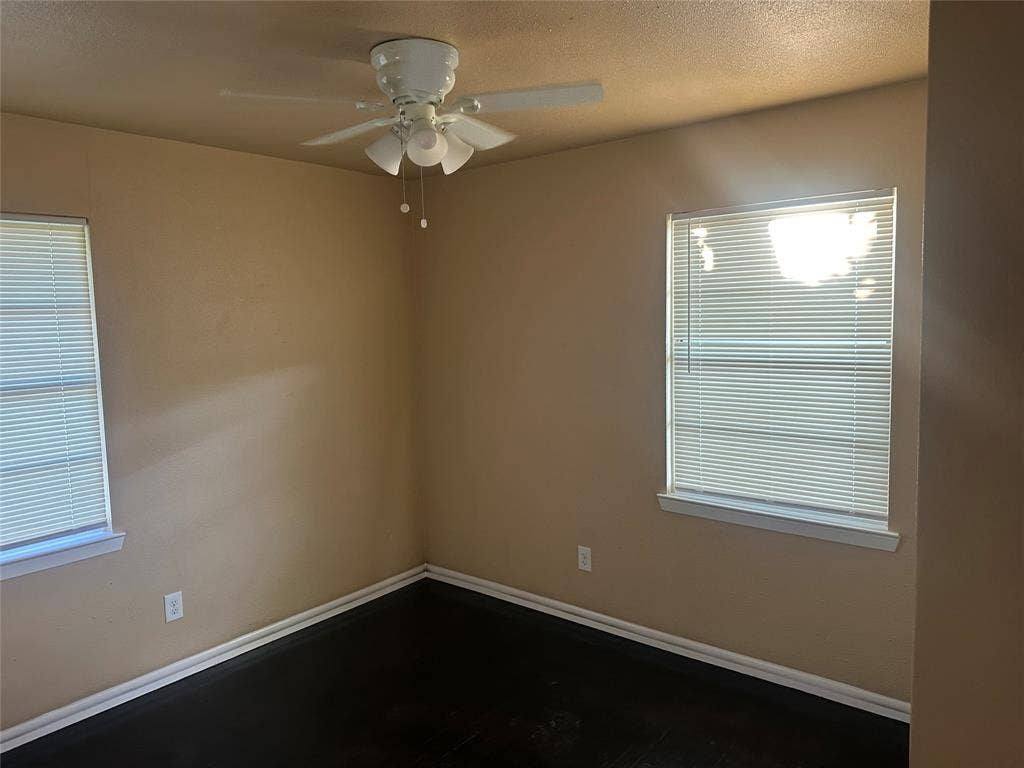 11809 Oberlin Drive, Dallas, TX 75243 Dark-toned wood-finish flooring, white multi-light ceiling fan, and windows equipped with horizontal blinds