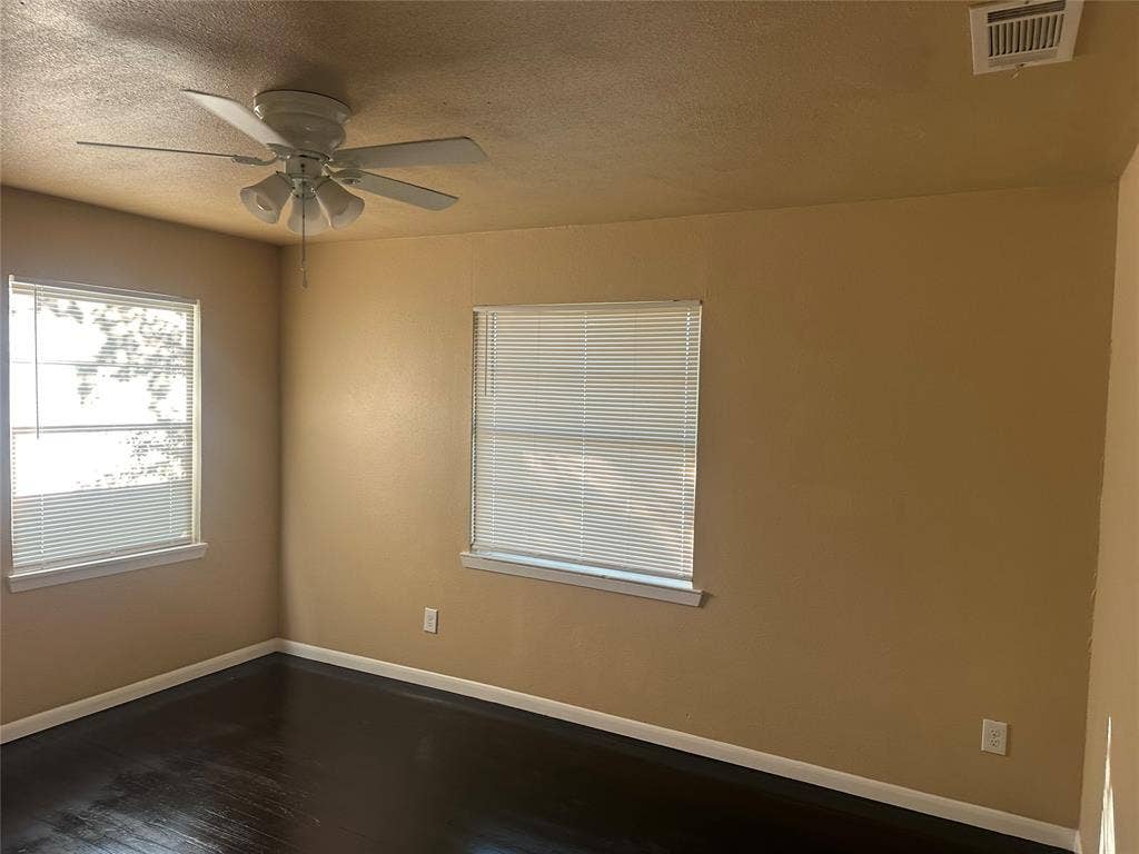 11809 Oberlin Drive, Dallas, TX 75243 Room featuring wood-finish flooring, two windows with horizontal blinds, and a white ceiling fan with integrated lighting
