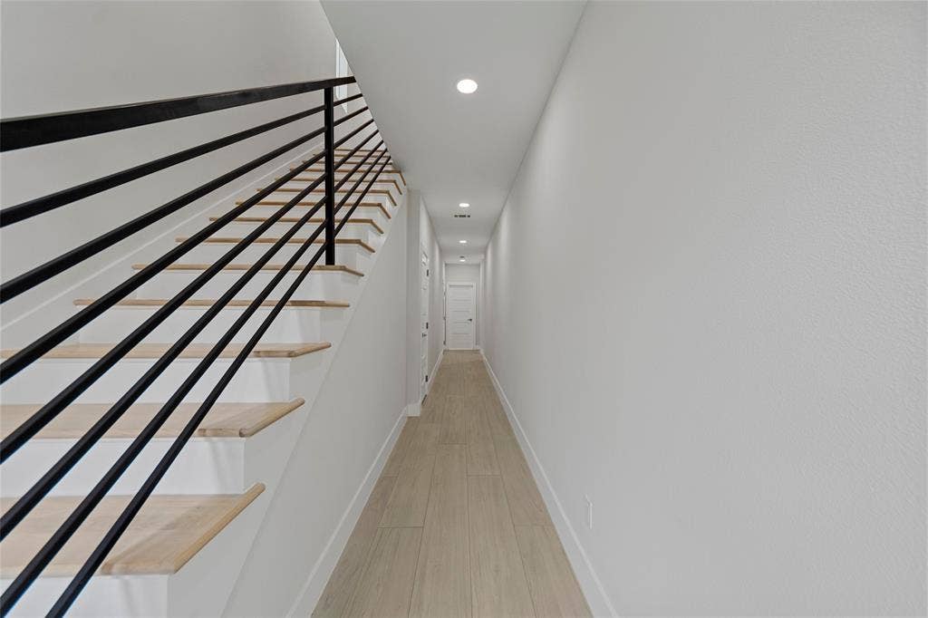 2503 Crossman Avenue, Dallas, TX 75212 Staircase featuring wood-finish treads and a matte black horizontal railing, wood-finish flooring, and recessed ceiling lighting
