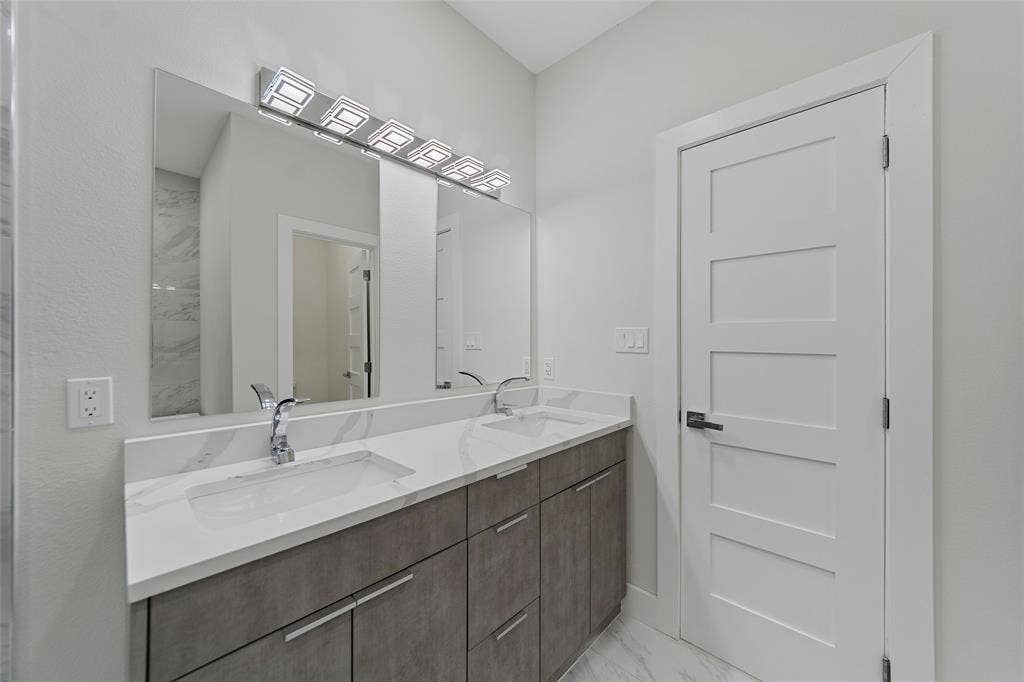 2503 Crossman Avenue, Dallas, TX 75212 Dual vanity featuring a white countertop with integrated sinks, chrome fixtures, flat-panel cabinetry, a full-width mirror, and multi-light LED vanity lighting