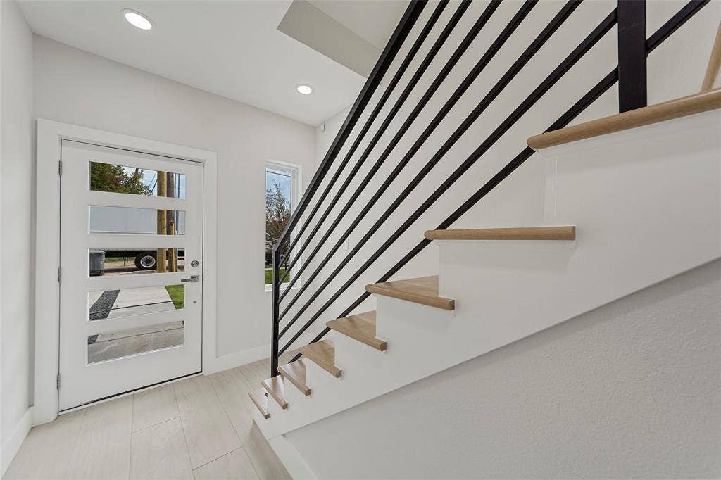 2503 Crossman Avenue, Dallas, TX 75212 Entryway featuring a white door with horizontal glass panels, recessed ceiling lighting, light-toned tile flooring, and a staircase with wood-finish treads and a matte black metal railing