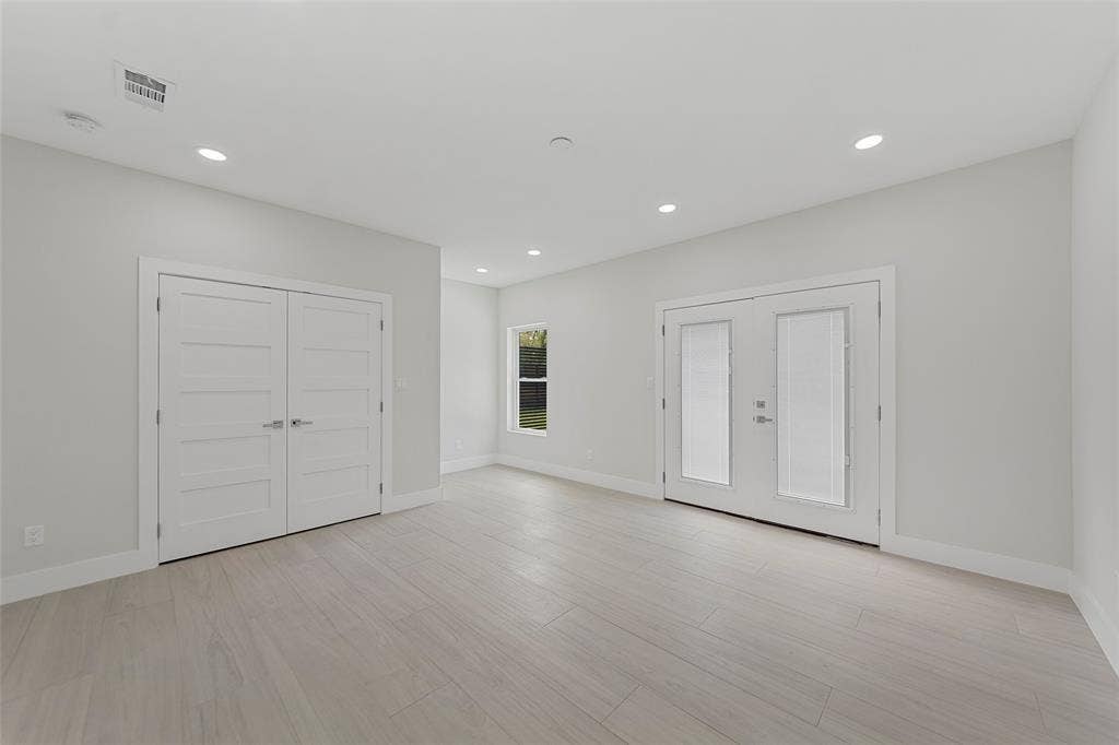 2503 Crossman Avenue, Dallas, TX 75212 Neutral-toned interior featuring wood-finish flooring, recessed lighting, double-door closet with shaker-style panels, and glass-paneled double doors