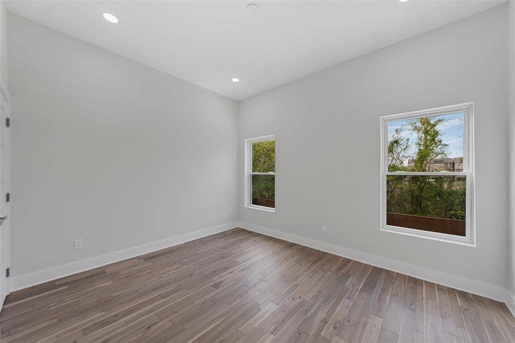 2503 Crossman Avenue, Dallas, TX 75212 High-ceiling room featuring neutral paint, wood-finish flooring, and two double-hung windows with exterior scenery