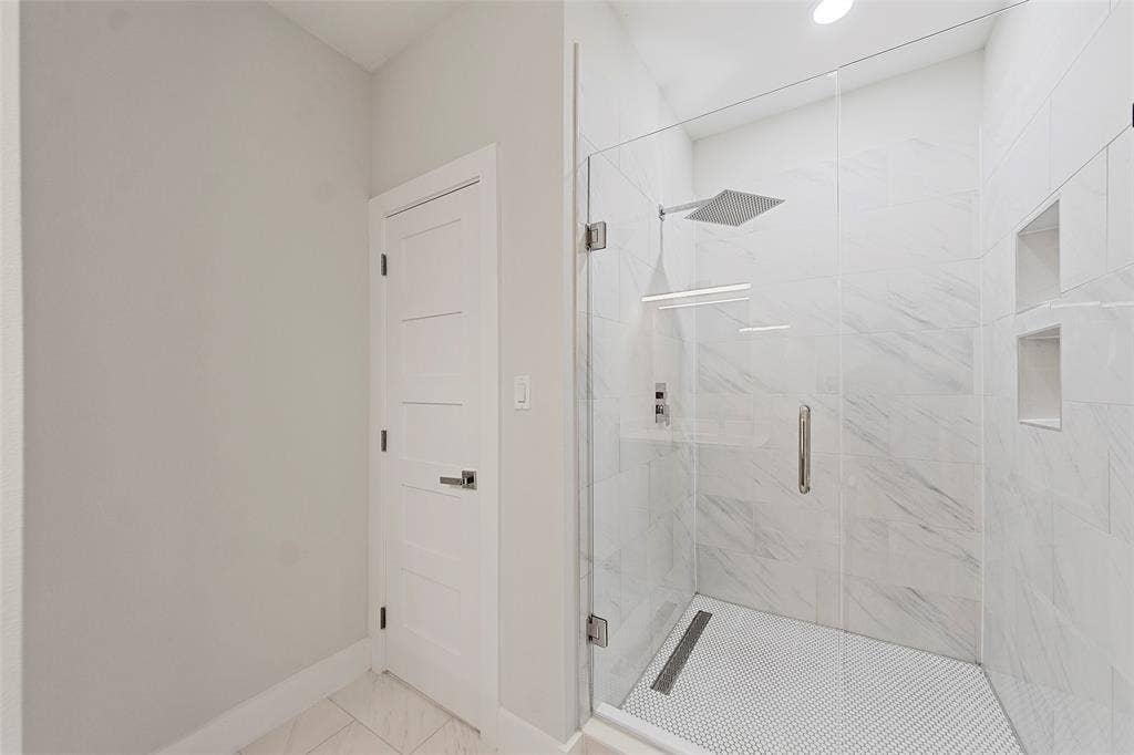 2503 Crossman Avenue, Dallas, TX 75212 Walk-in shower featuring a frameless glass enclosure, floor-to-ceiling stone-patterned tile, integrated recessed shelving, and a linear drain