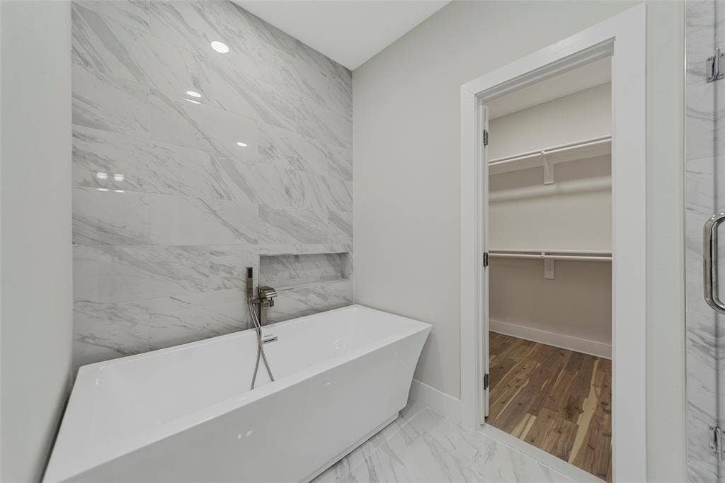 2503 Crossman Avenue, Dallas, TX 75212 Freestanding soaking tub with polished chrome hand-held faucet, recessed wall niche, full-height decorative tile accent wall, and porcelain tile flooring