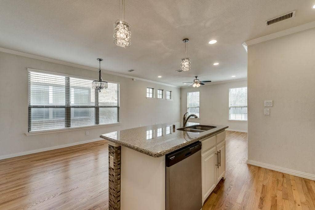 636 S Greenville Avenue, Richardson, TX 75081 Kitchen featuring ceiling fan with notable chandelier, white cabinetry, light hardwood / wood-style flooring, a center island with sink, and stainless steel dishwasher